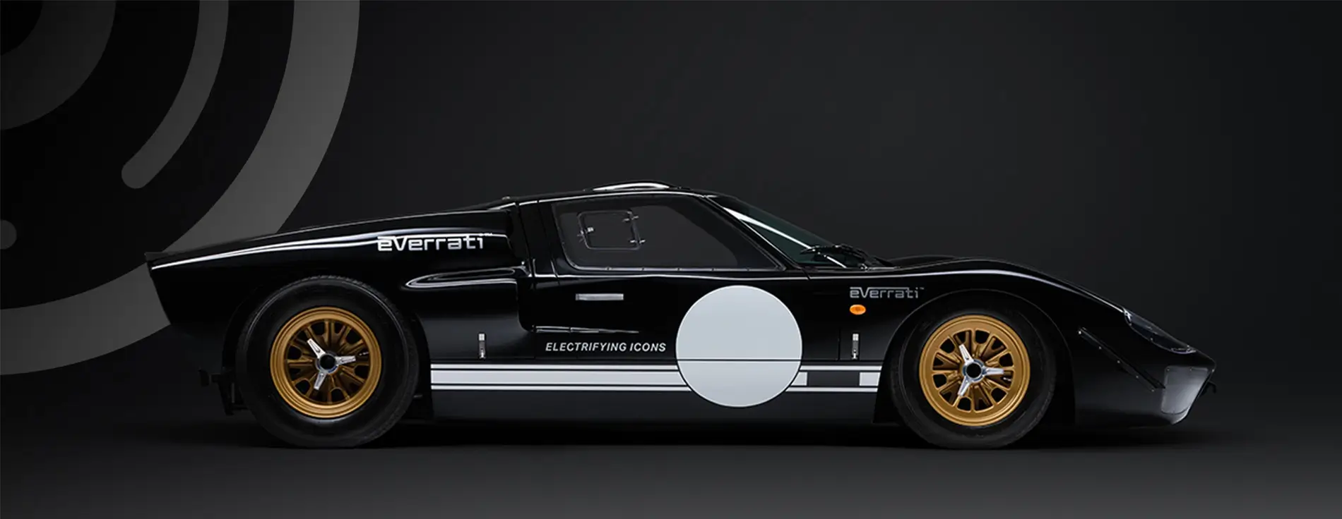 A black Everrati electric sports car in side profile against a dark background, featuring gold wheels, white circular decals on the doors, and the text “Electrifying Icons” along the lower body.