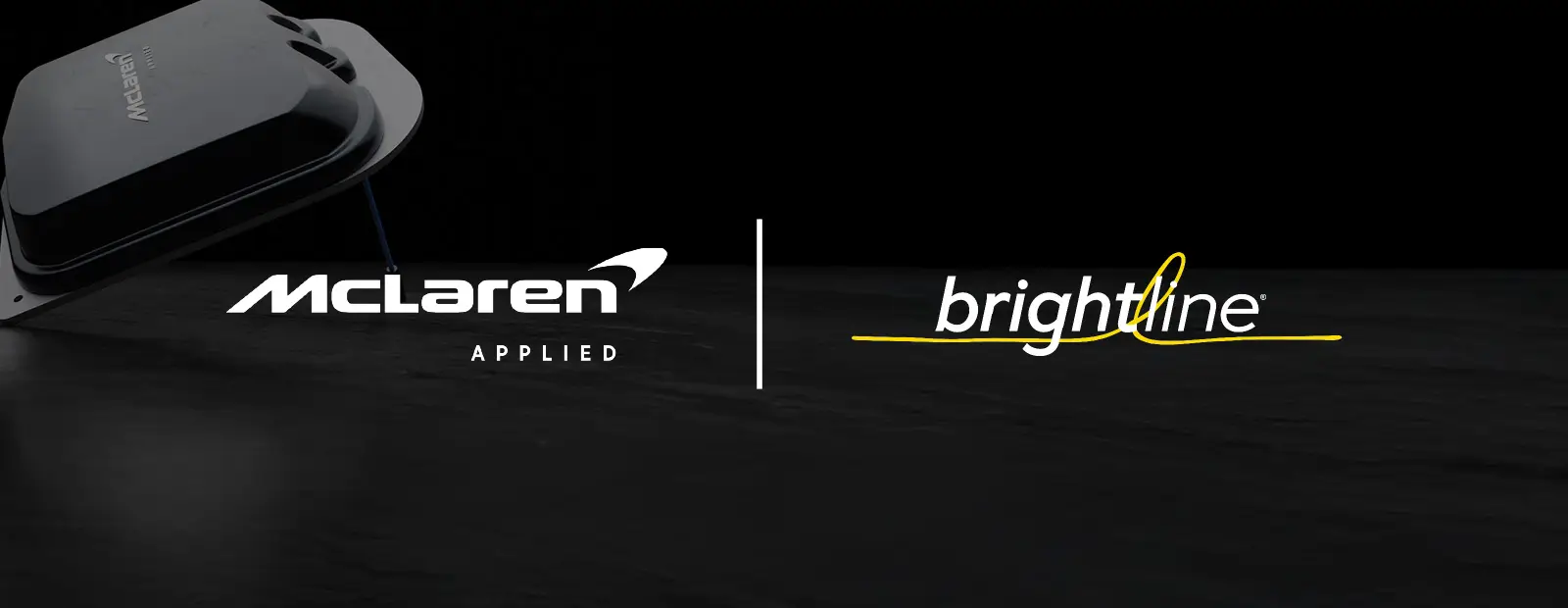 Two logos on a dark background: “McLaren Applied” in white on the left and “brightline” in white lowercase letters with a yellow underline and loop on the right, separated by a thin vertical line. An Active Antenna unit is partially visible in the top left corner.