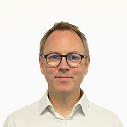 Matt Kitchin, Director, Products, programmes and engineering, wearing a plain white collared shirt, posed against a solid light background in a portrait-style image.