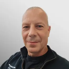 Dave Strudwick, Director, Operations wearing a black zip-up jacket with a visible logo on the left side, posed against a plain light gray background