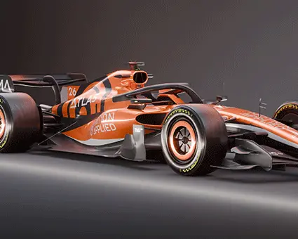 Side view of an orange Formula‑style race car with ATLAS and Motion Applied branding, shown in a studio setting against a dark background.
