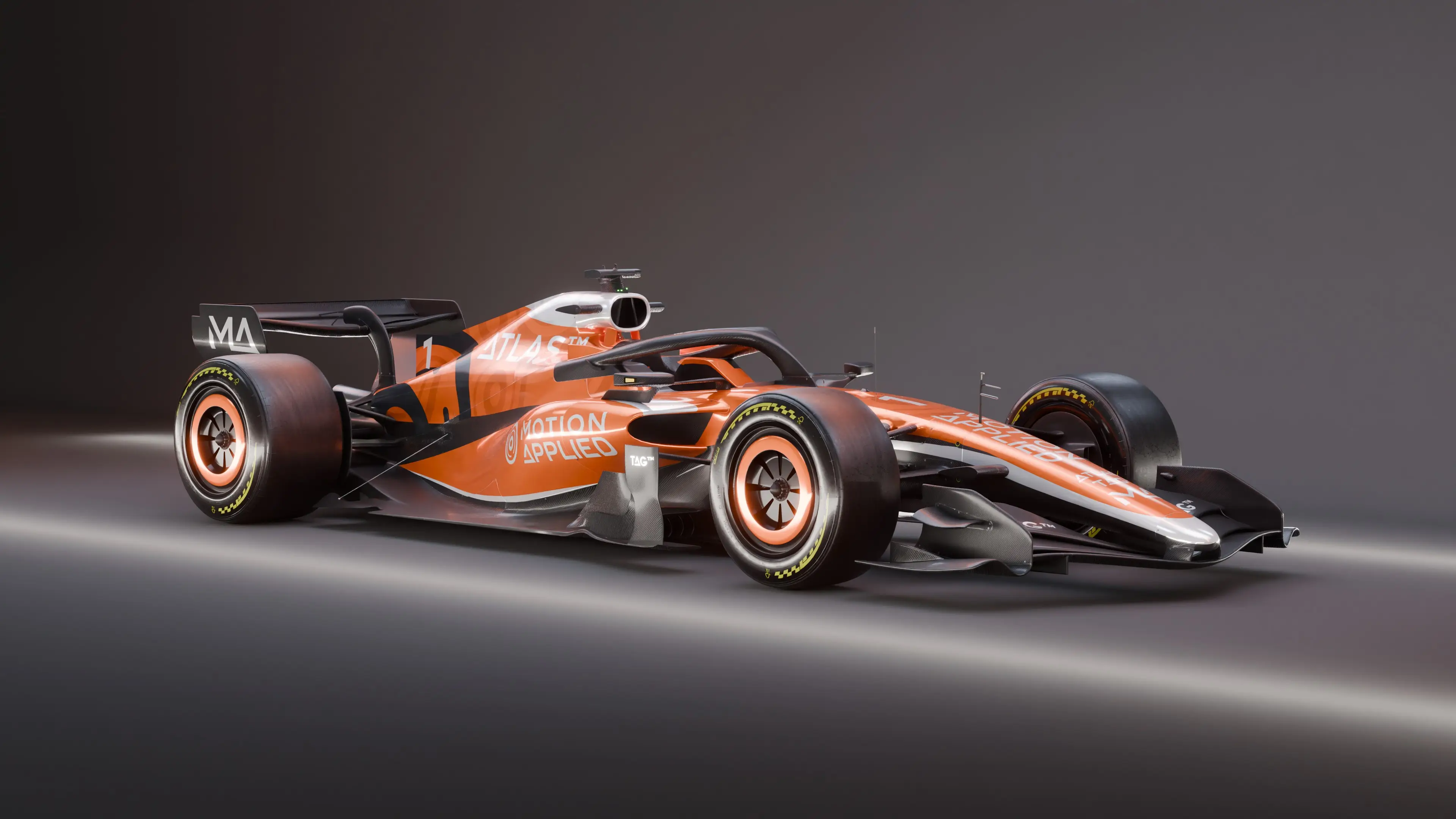 Side view of an orange Formula‑style race car with ATLAS and Motion Applied branding, shown in a studio setting against a dark background.