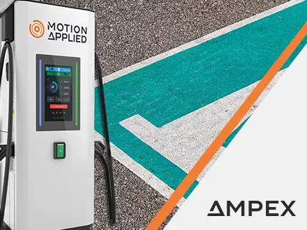 Motion Applied electric vehicle charging station with a digital display and cable, positioned beside a painted road arrow, with AMPEX branding visible on the right.