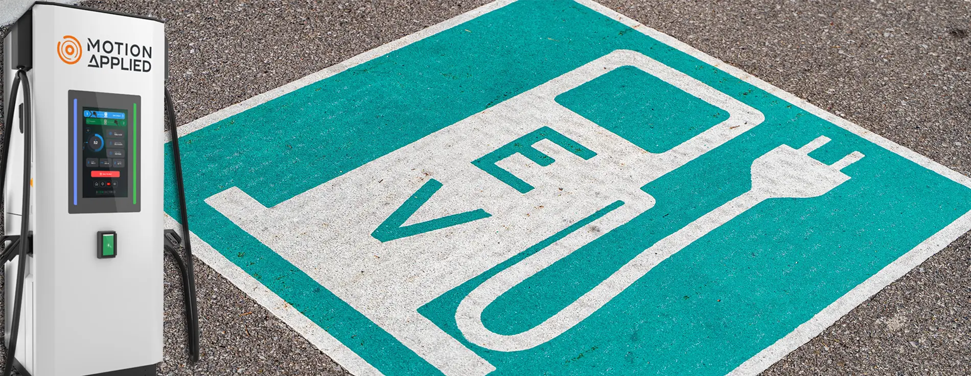Motion Applied electric vehicle charging station with a digital display and cable, positioned beside a painted road arrow, with AMPEX branding visible on the right.